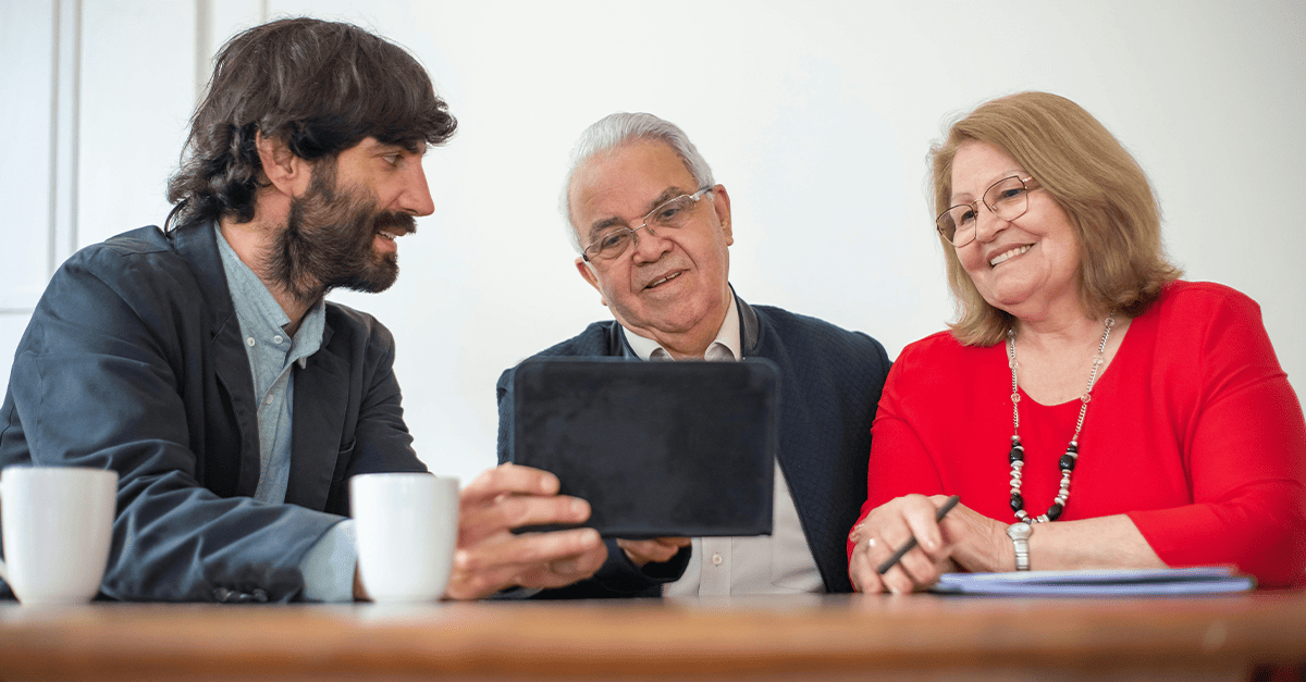 Tre persone sedute ad una scrivania mentre utilizzano un tablet